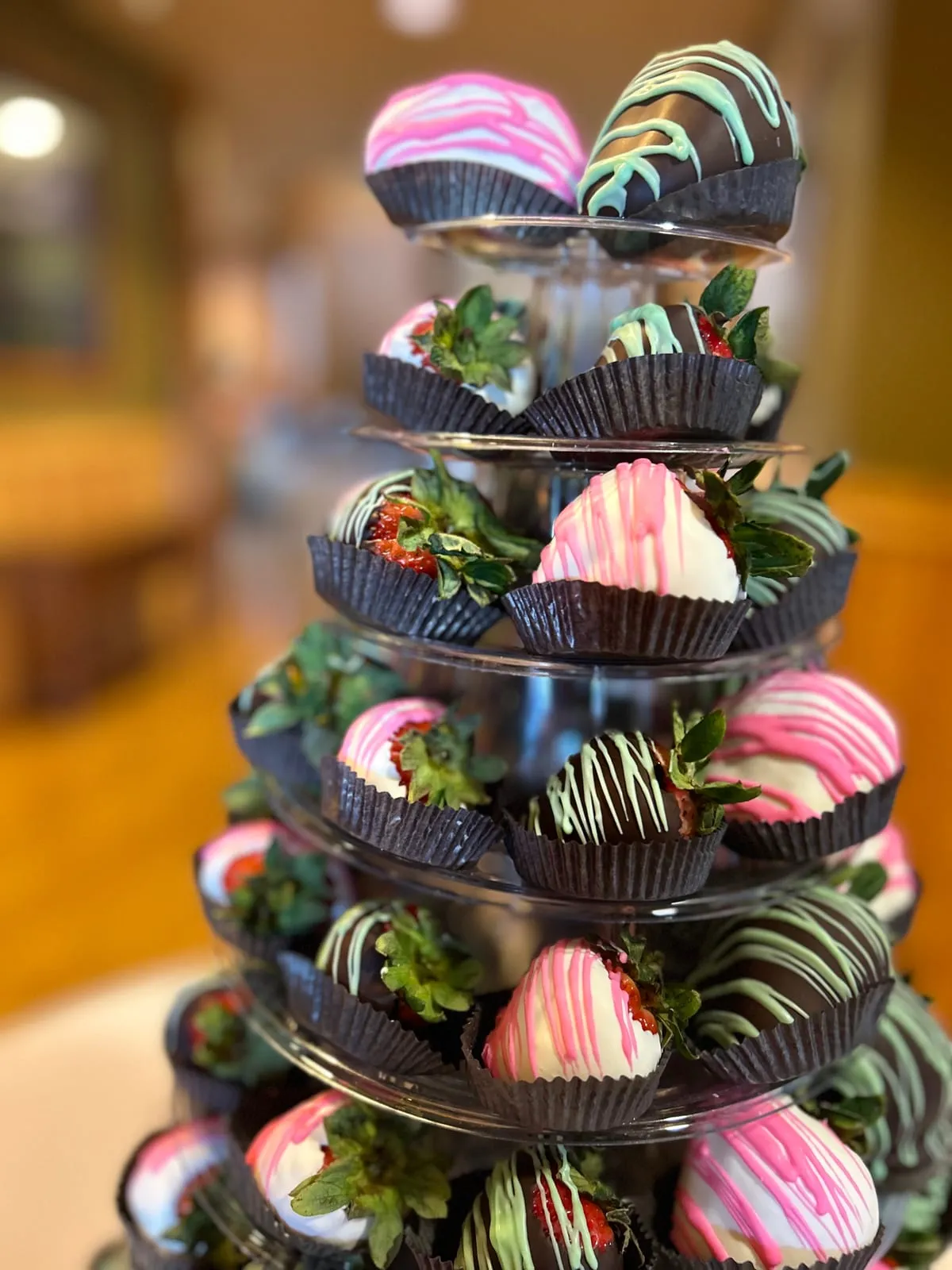 A close-up of an artisan Event Tower of chocolate-dipped strawberries and macarons at a catered event
