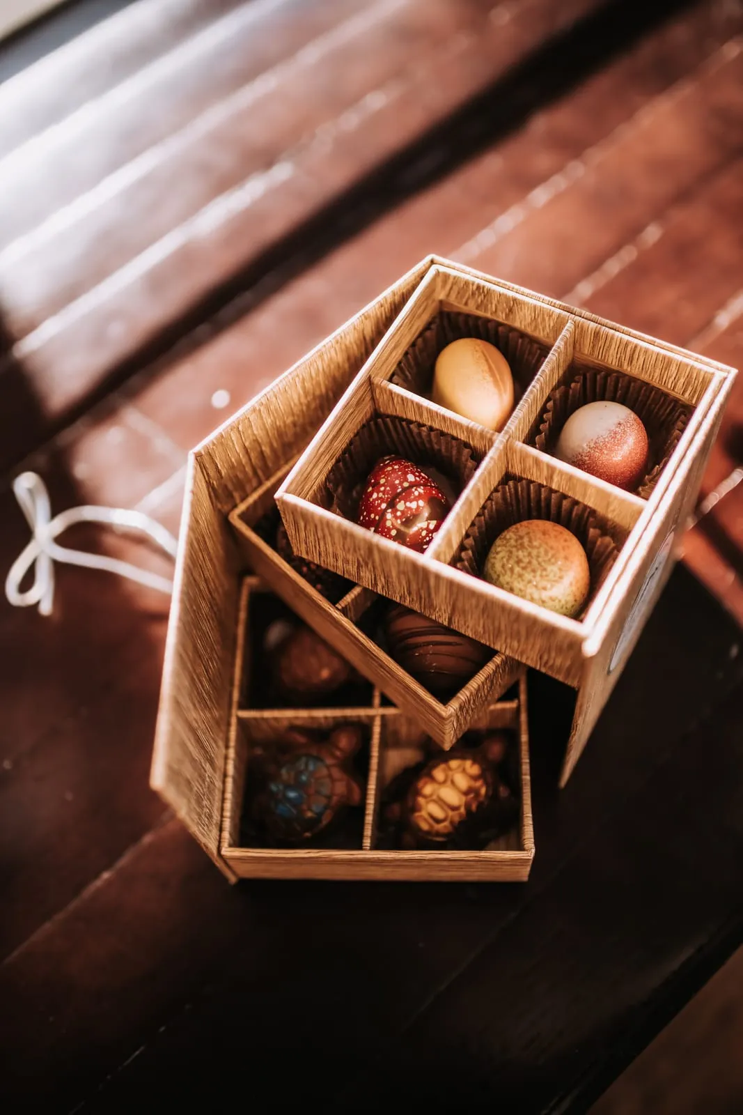 An open wooden box of hand-painted artisan chocolates and truffles