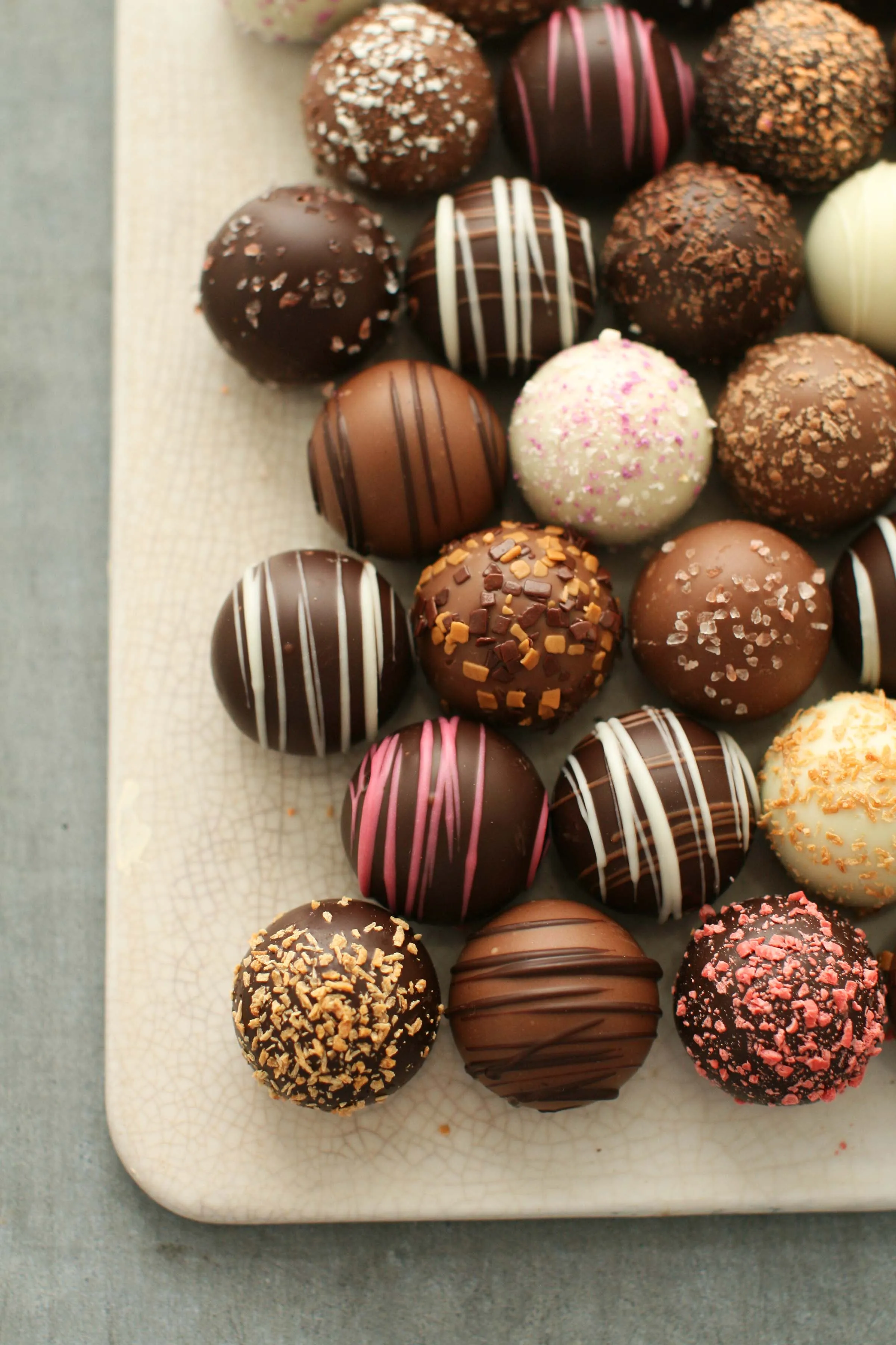 Hand-rolled artisan chocolate truffles on a ceramic tray